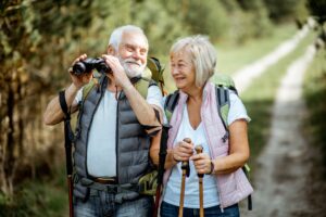 A happy senior citizen couple hiking on a trail and enjoying nature.